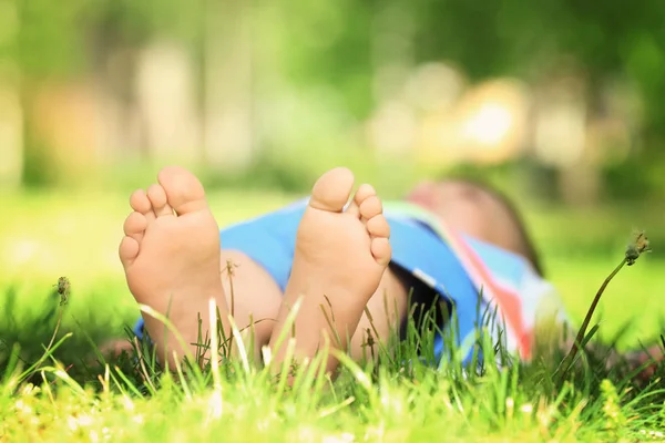 Πόδια του αγοριού ξαπλωμένος στο γρασίδι — Φωτογραφία Αρχείου