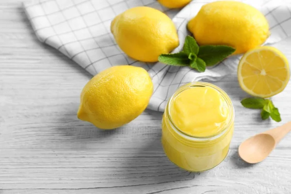 Glass jar with yummy lemon curd on white wooden table — Stock Photo, Image