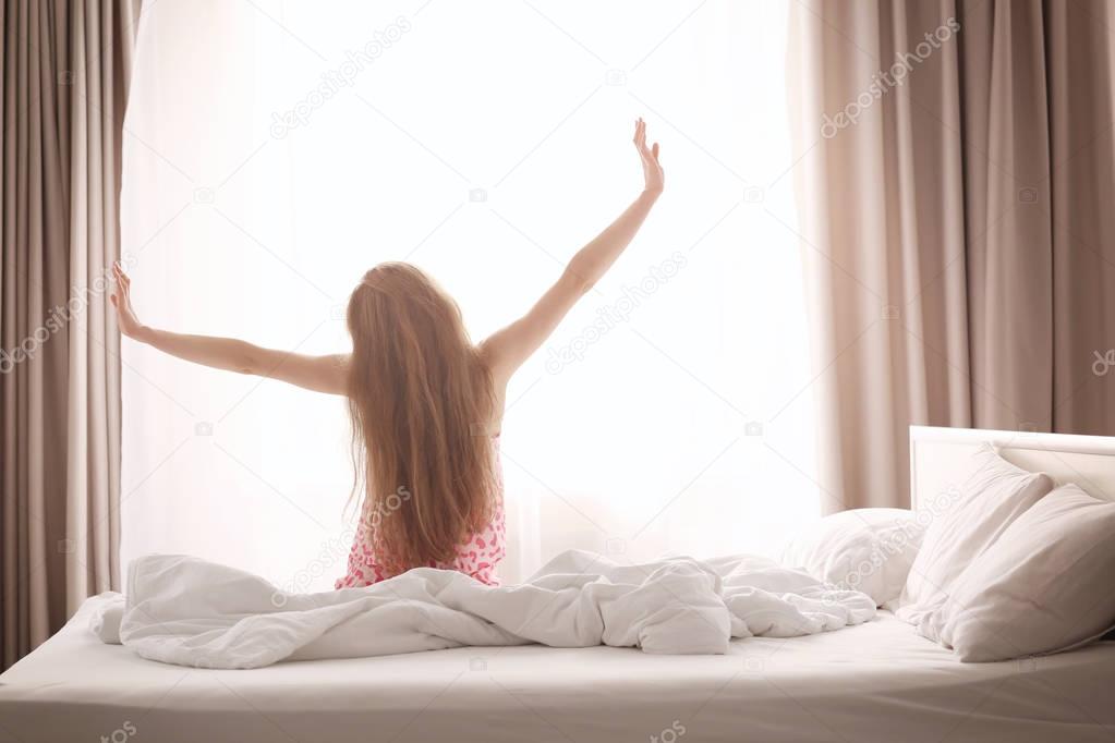 Morning of beautiful young woman sitting on bed at home