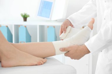 Doktor hastanın bacak üzerine uygulanan bandaj 