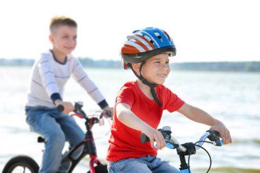 Sevimli küçük çocuklar güneşli günde Nehri yakınında bisiklet sürme