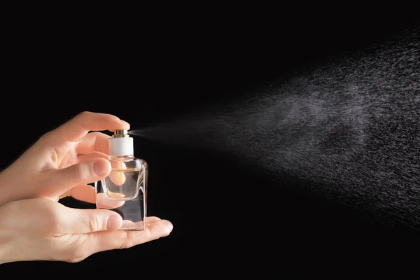 Female hand spraying perfume