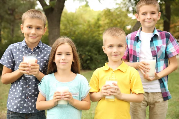 Söta barn med glas mjölk i parken — Stockfoto