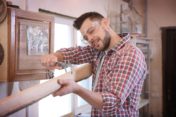 Carpintero midiendo tablón de madera —  Fotos de Stock