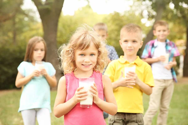 Lindos niños con vasos de leche en el parque — Foto de Stock