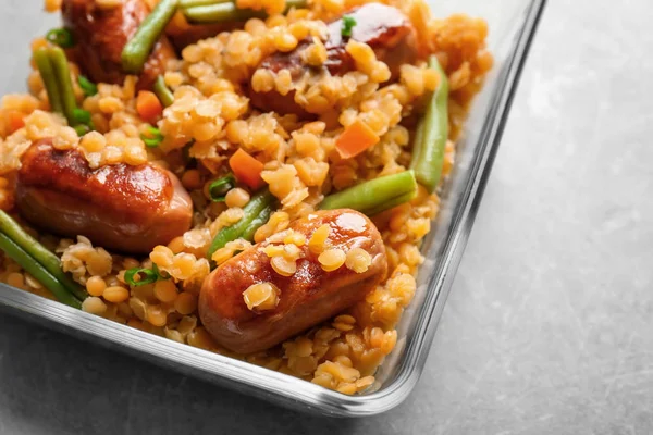 Tigela de vidro com mingau de lentilha saborosa, salsichas e legumes — Fotografia de Stock