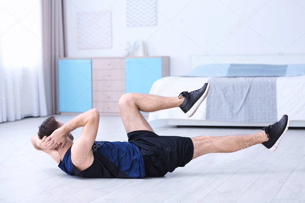 Young sportive man doing bicycle crunch exercise at home