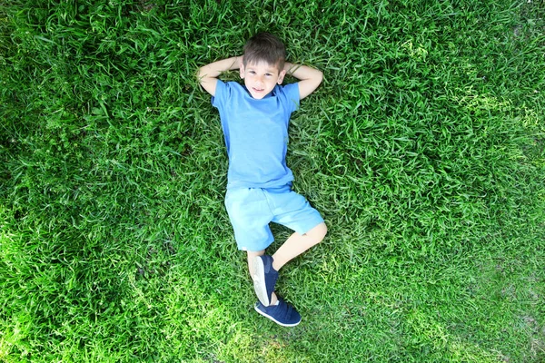 Ładny, mały chłopiec, leżąc na trawie — Zdjęcie stockowe