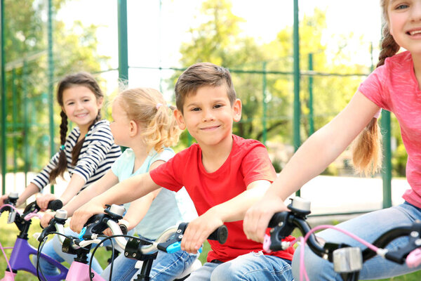 Cute children with bicycles in park on sunny day