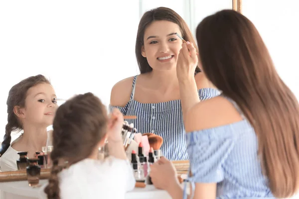 Mulher e filha aplicando maquiagem — Fotografia de Stock