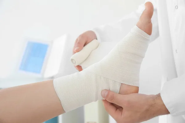 Médico aplicando bandagem na perna do paciente — Fotografia de Stock