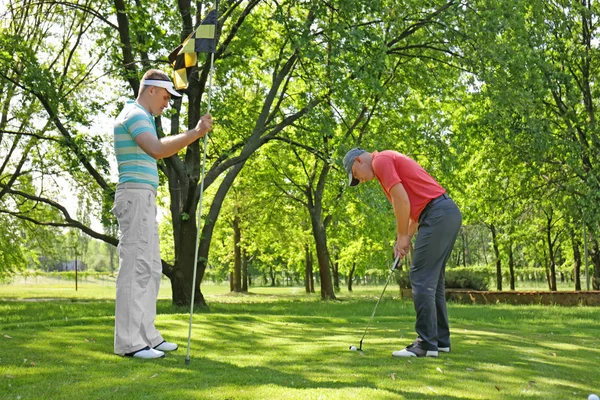 Hombres jóvenes jugando al golf en el campo en un día soleado —  Fotos de Stock