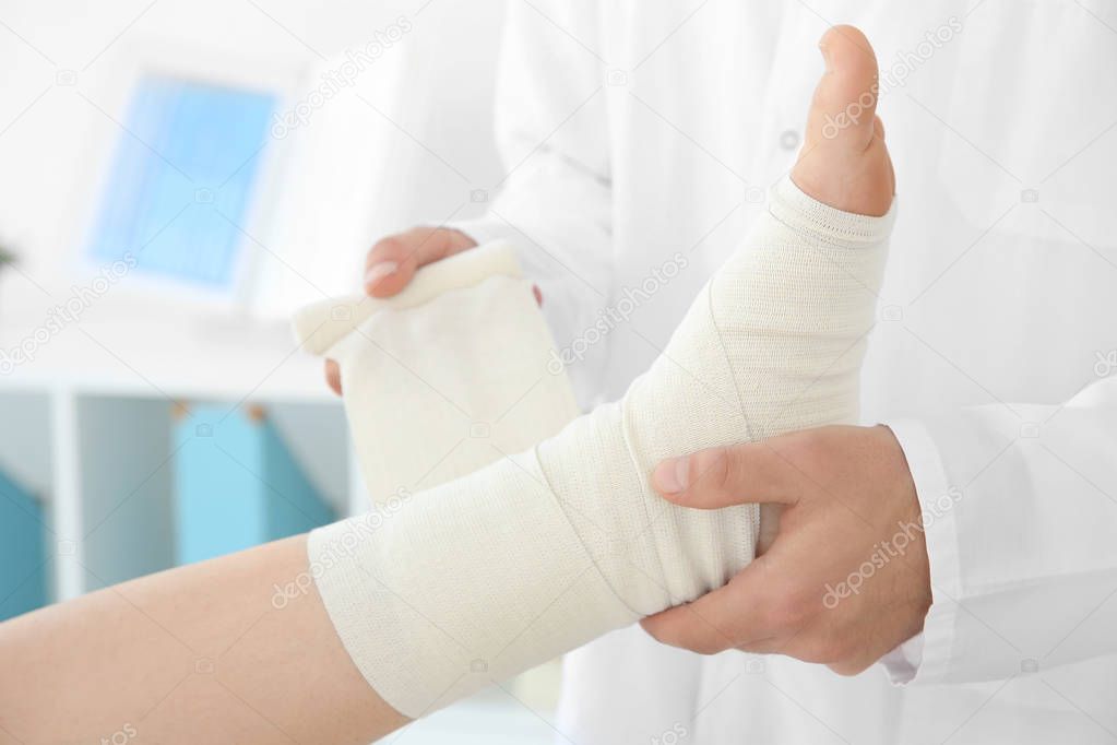 Doctor applying bandage onto patient's leg 