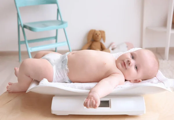 Baby lying on scales in room — Stock Photo, Image