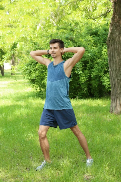 Atletico giovane che fa ciclismo esercizio crunch mentre in piedi su erba nel parco verde primaverile — Foto Stock