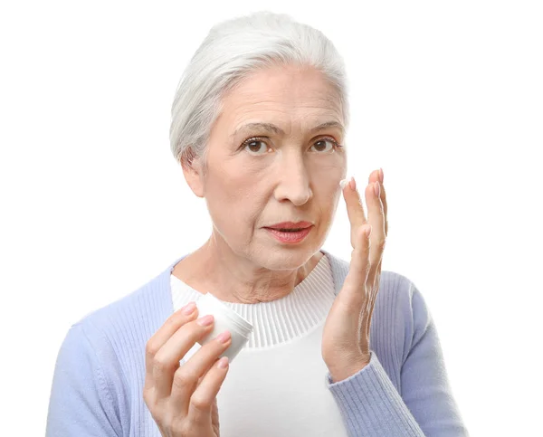 Пожилая женщина наносит крем — стоковое фото