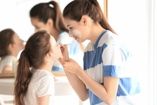 Vrouw en dochter toe te passen gezichtsmasker — Stockfoto