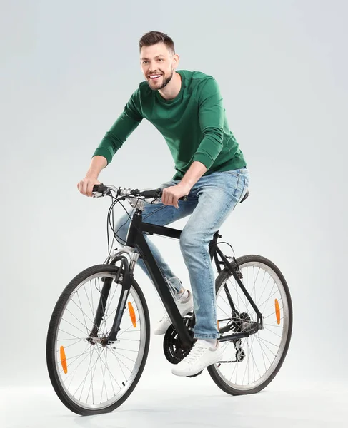 明るい背景でハンサムな若い男乗って自転車 — ストック写真