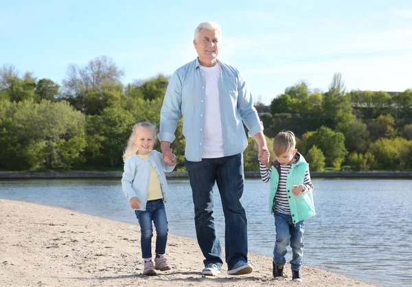 Abuelo con niños en la orilla del río — Foto de Stock