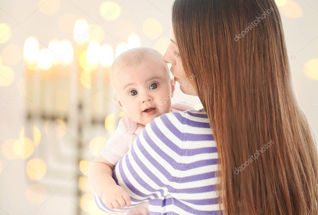 Mother with little child on blurred festive lights background, Baby First Hanukkah