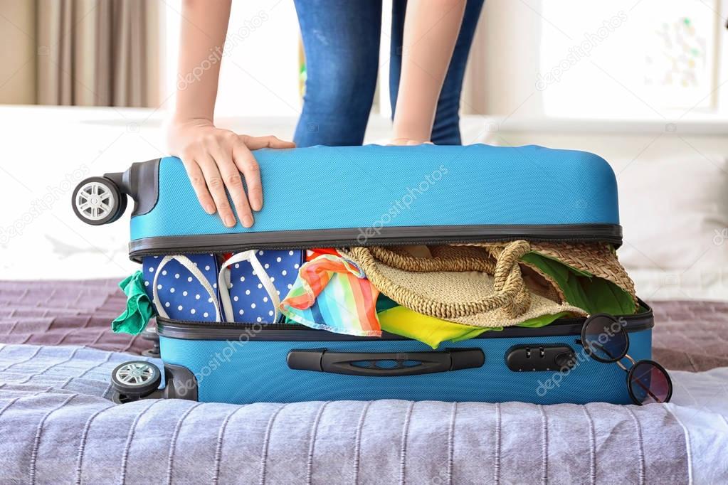 Woman trying to lock suitcase 