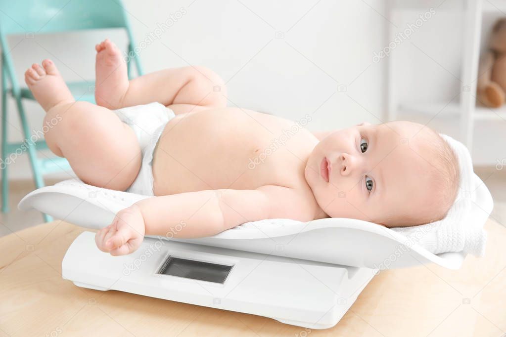 Baby lying on scales in room