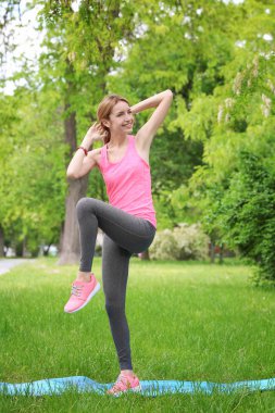 Mat yeşil Bahar park dururken Bisiklet crunch egzersiz yaparak atletik genç kadın