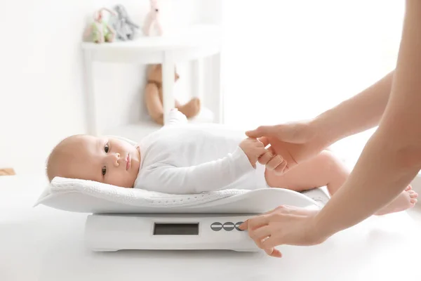 Mother weighting baby on scales in room — Stock Photo, Image