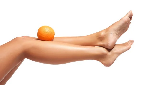 Jambes féminines et orange sur blanc — Photo