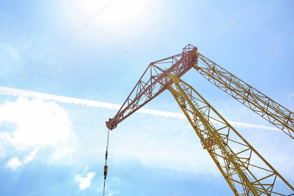 Hoisting crane against sky