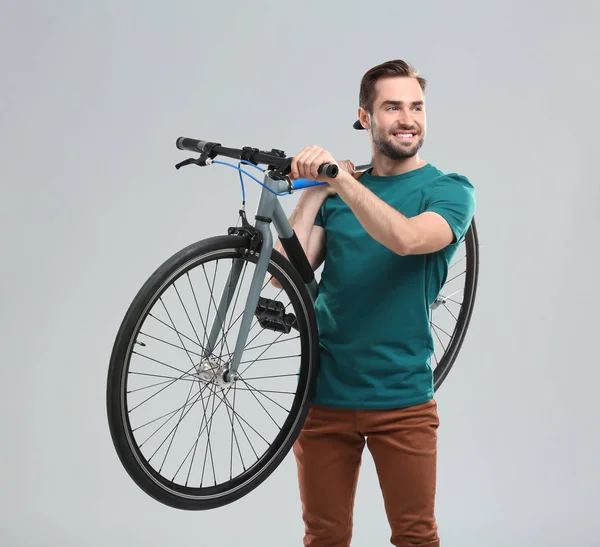 Stilig ung man med cykel på ljus bakgrund — Stockfoto