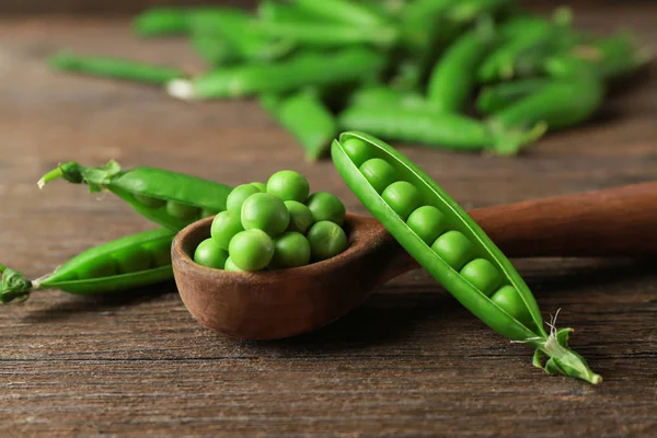 Colher de madeira com ervilhas verdes frescas — Fotografia de Stock