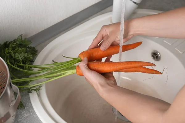 Mujer lavando zanahorias frescas — Foto de Stock
