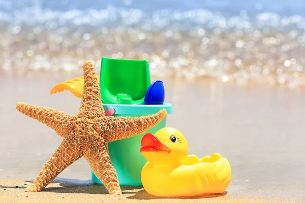 Renkli oyuncaklar ve denizyıldızı kum üzerinde — Stok fotoğraf