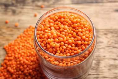 Ahşap arka plan üzerinde kırmızı mercimek kavanoz