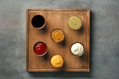 Ahşap plaka gri arka plan üzerinde farklı sos ile