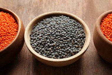 Ahşap arka plan üzerinde siyah ve kırmızı mercimek ile kase