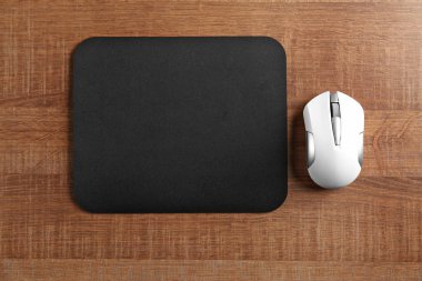 Blank mat and wireless mouse on wooden background clipart