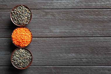 Ahşap arka plan üzerinde siyah ve kırmızı mercimek ile kase