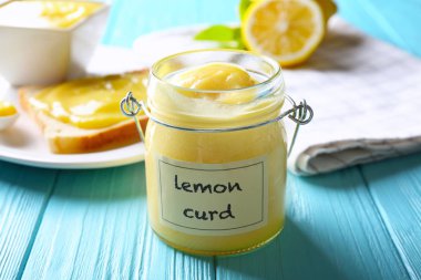 Glass jar with delicious lemon curd on wooden table clipart