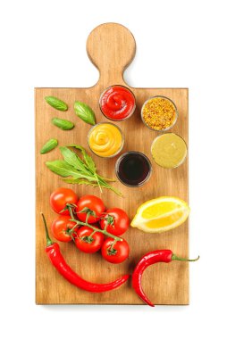 Farklı sos ve beyaz arka plan üzerinde sebze ile ahşap tahta