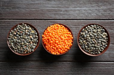 Ahşap arka plan üzerinde siyah ve kırmızı mercimek ile kase