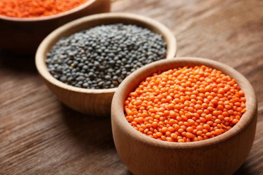 Ahşap arka plan üzerinde siyah ve kırmızı mercimek ile kase