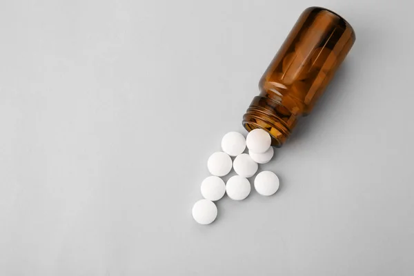 Glass bottle and pills on light background — Stock Photo, Image