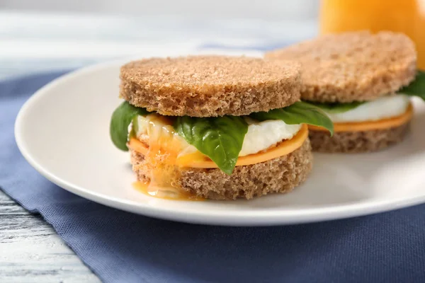 Delicious sandwiches with over easy egg,  cheese and basil leaves on kitchen table — Stock Photo, Image