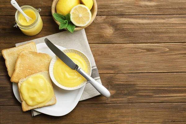 Composición con tostadas frescas y deliciosa cuajada de limón sobre mesa de madera —  Fotos de Stock