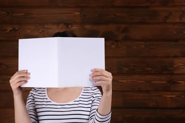 Mujer sosteniendo libro abierto con cubierta en blanco sobre fondo de madera —  Fotos de Stock