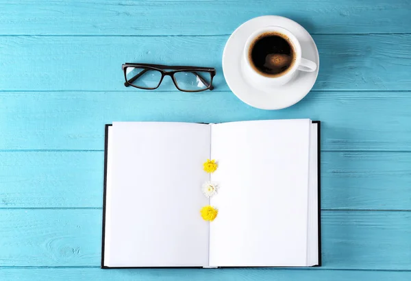 Öppen bok med tomma sidor, kopp kaffe och glasögon på färg trä bakgrund — Stockfoto