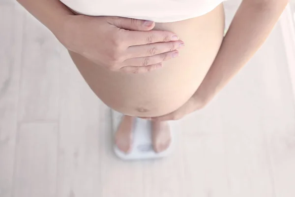 Wanita hamil berdiri di timbangan di rumah. Konsep peningkatan berat badan kehamilan — Stok Foto