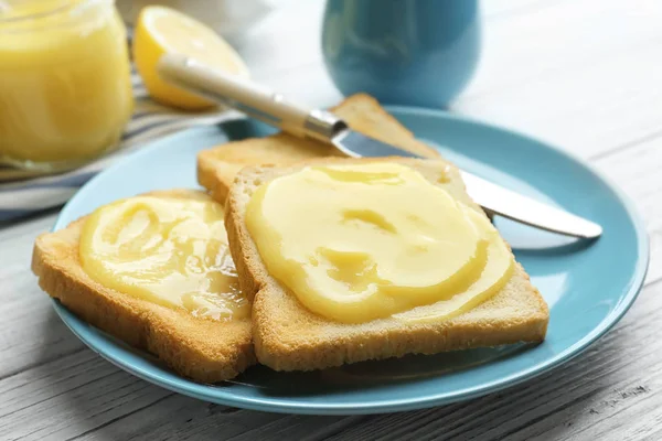 Placa con tostadas frescas y deliciosa cuajada de limón en la mesa de madera, primer plano — Foto de Stock